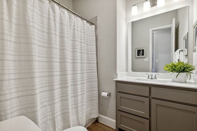 bathroom featuring toilet, hardwood / wood-style flooring, walk in shower, and vanity