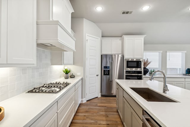 kitchen with stainless steel appliances, sink, white cabinets, backsplash, and dark wood-type flooring