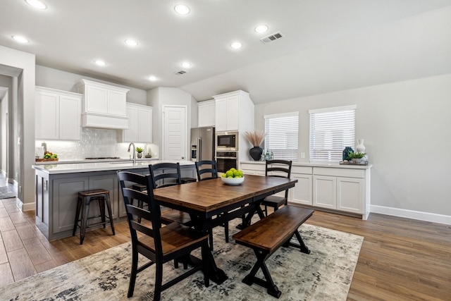 dining area featuring dark wood-type flooring and vaulted ceiling