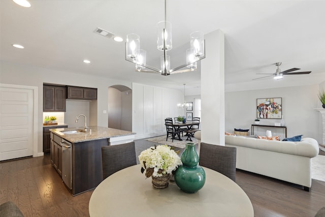 kitchen featuring sink, decorative light fixtures, ceiling fan with notable chandelier, dark brown cabinets, and light stone countertops