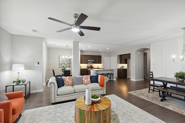 living room featuring ceiling fan with notable chandelier and dark hardwood / wood-style floors