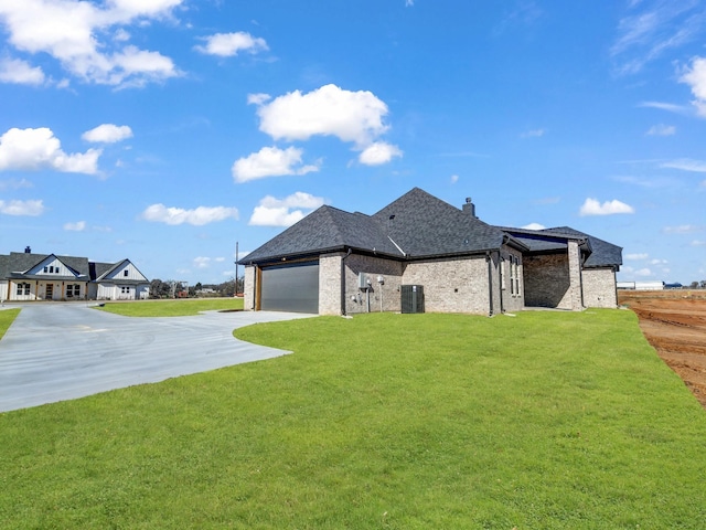 back of house with a yard, central AC unit, and a garage