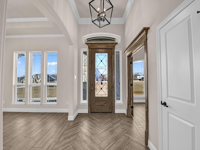 entryway with light parquet floors, an inviting chandelier, a healthy amount of sunlight, and crown molding