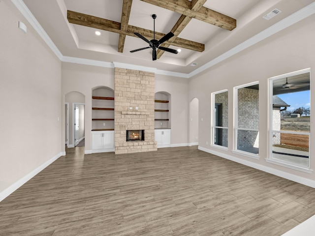 unfurnished living room with coffered ceiling, a towering ceiling, a fireplace, and beam ceiling