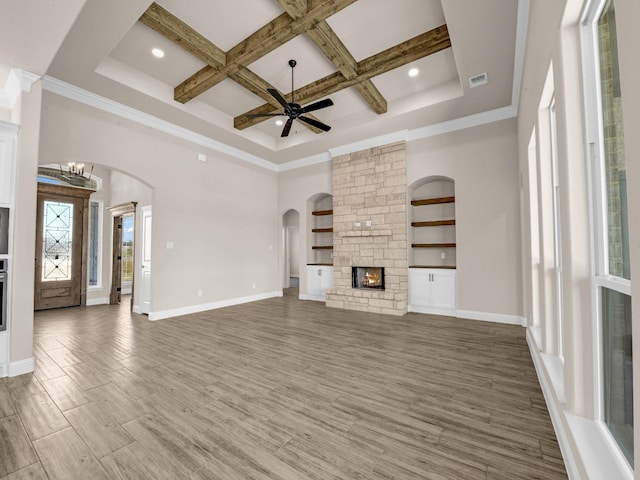 unfurnished living room with coffered ceiling, a towering ceiling, ceiling fan with notable chandelier, a fireplace, and beamed ceiling