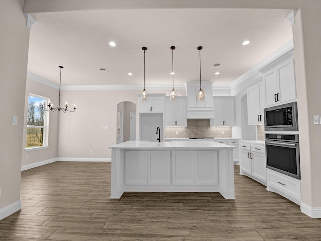 kitchen with a center island with sink, white cabinets, stainless steel oven, and built in microwave