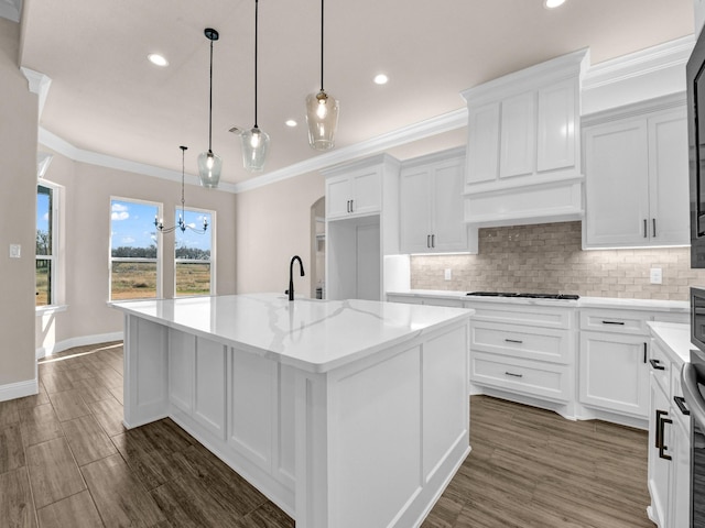 kitchen with decorative light fixtures, white cabinets, light stone countertops, a kitchen island with sink, and a notable chandelier