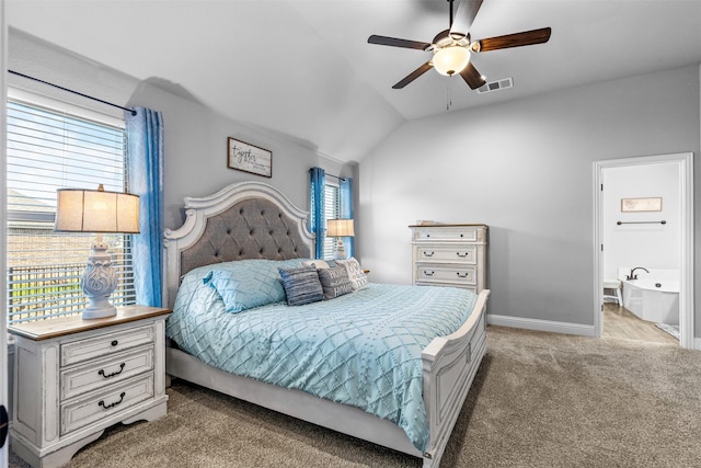 carpeted bedroom with ceiling fan, multiple windows, ensuite bathroom, and lofted ceiling