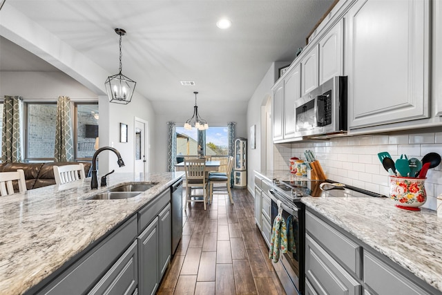 kitchen with light stone counters, stainless steel appliances, gray cabinets, and sink