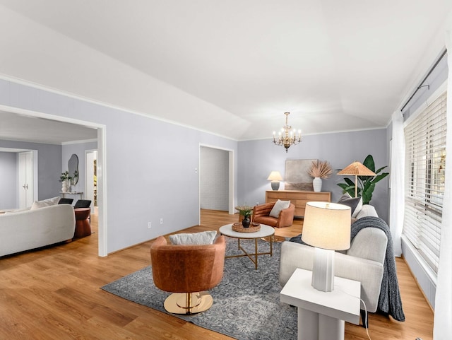 living room with vaulted ceiling, an inviting chandelier, light hardwood / wood-style floors, and crown molding