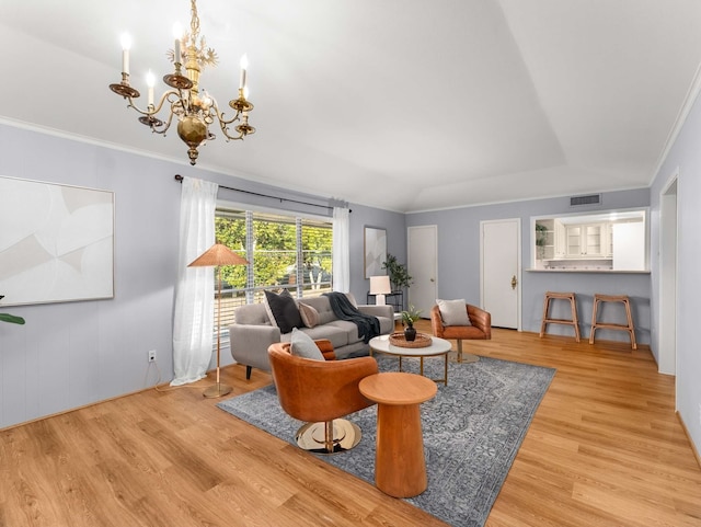 living room featuring ornamental molding, a notable chandelier, and light hardwood / wood-style floors