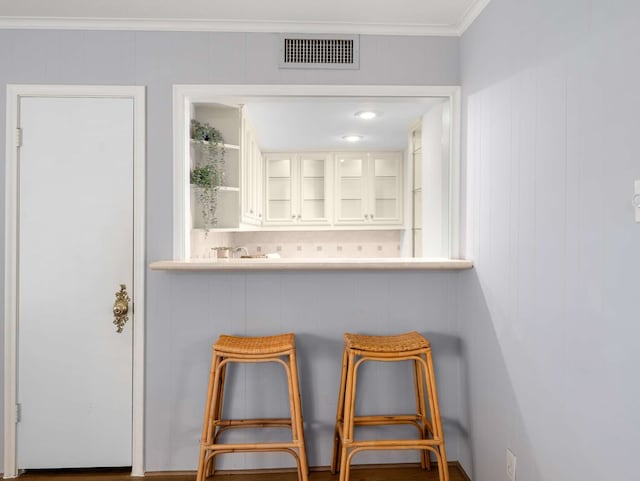 bar featuring white cabinets and crown molding