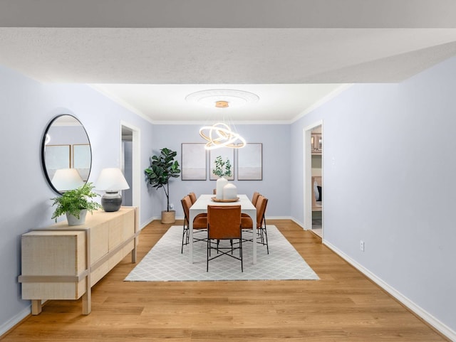 dining area with an inviting chandelier, ornamental molding, and light hardwood / wood-style floors