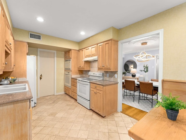 kitchen featuring white appliances, hanging light fixtures, sink, and light brown cabinets