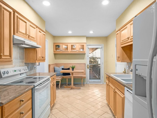 kitchen with white appliances, dark stone countertops, backsplash, sink, and light tile patterned flooring