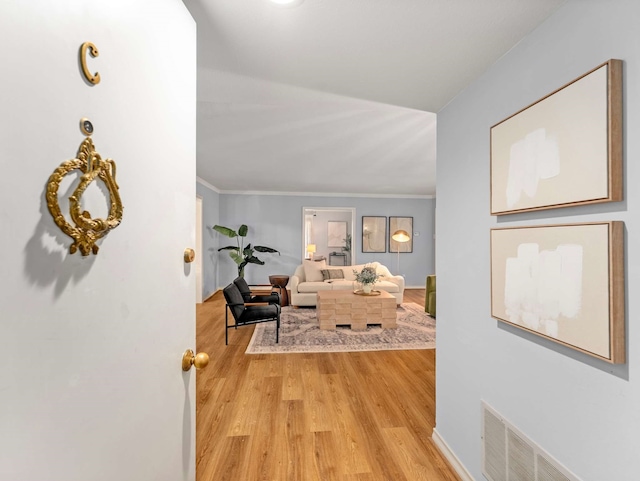 hallway with light hardwood / wood-style floors and ornamental molding