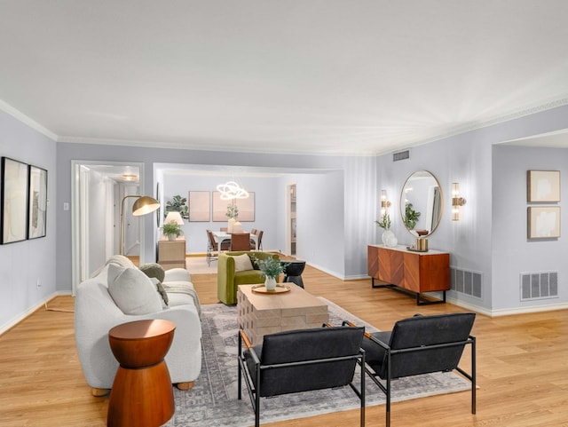 living room with light wood-type flooring, crown molding, and a chandelier