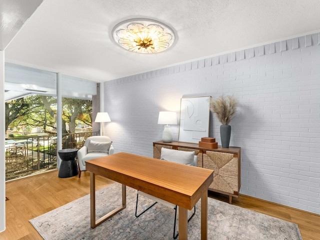 office area featuring light hardwood / wood-style flooring and brick wall