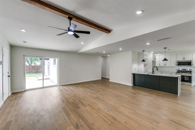 unfurnished living room featuring sink, ceiling fan, vaulted ceiling with beams, and light hardwood / wood-style flooring