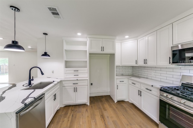 kitchen with white cabinets, stainless steel appliances, hanging light fixtures, kitchen peninsula, and sink