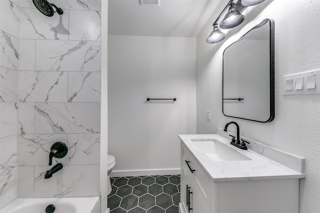 full bathroom featuring tile patterned flooring, toilet, vanity, tiled shower / bath, and a textured ceiling