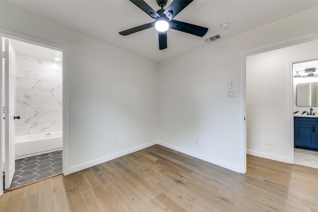 unfurnished bedroom with sink, ceiling fan, light hardwood / wood-style floors, and connected bathroom