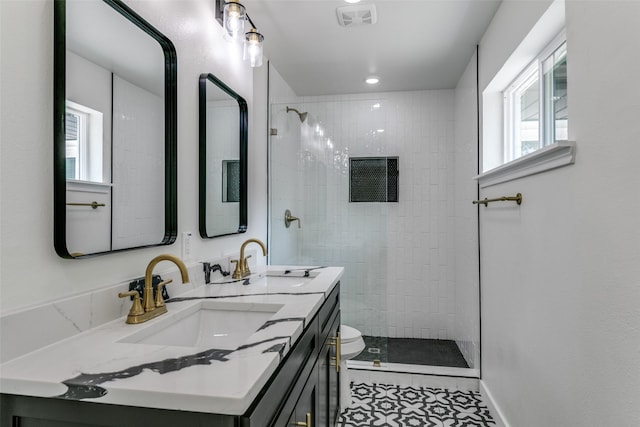 bathroom featuring toilet, a tile shower, a wealth of natural light, and vanity