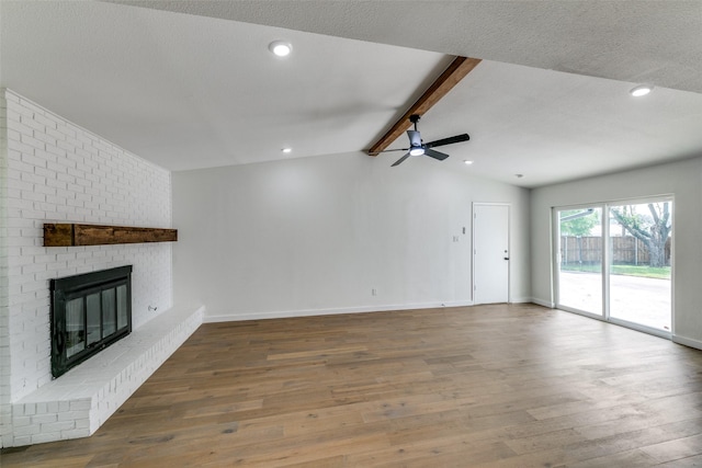 unfurnished living room featuring ceiling fan, dark wood-type flooring, vaulted ceiling with beams, and a fireplace