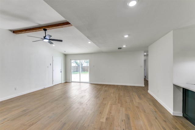 unfurnished living room featuring ceiling fan, light hardwood / wood-style flooring, and vaulted ceiling with beams