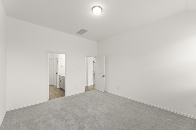 unfurnished bedroom featuring ensuite bath and light carpet