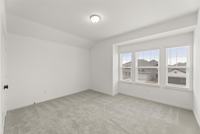 carpeted spare room with vaulted ceiling