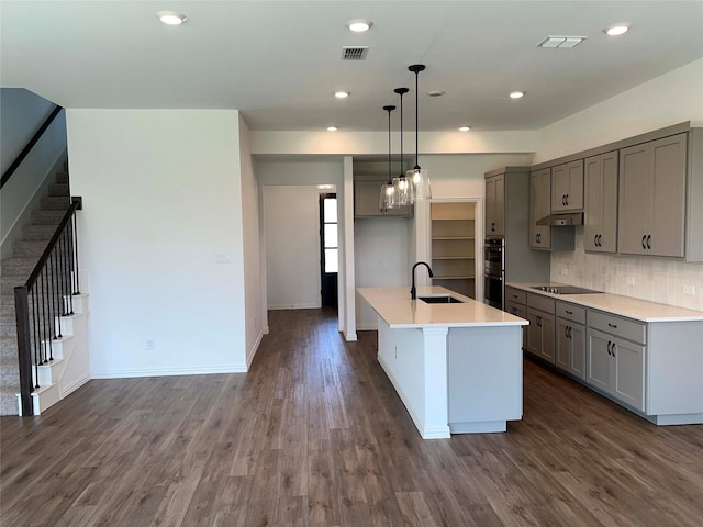 kitchen featuring dark hardwood / wood-style floors, decorative light fixtures, an island with sink, black electric cooktop, and sink