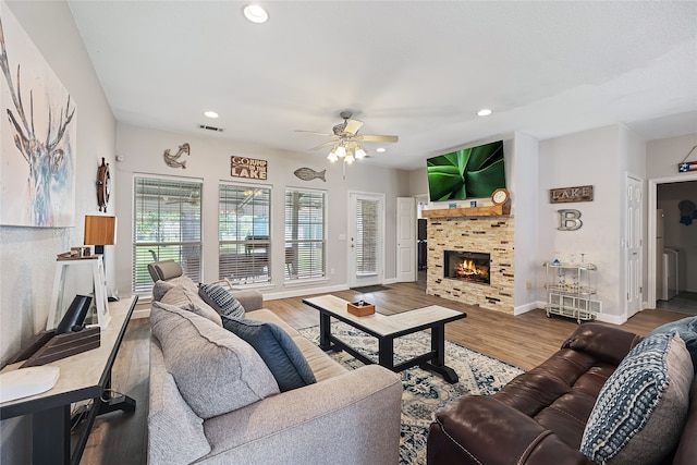 living room featuring hardwood / wood-style flooring, ceiling fan, and a tile fireplace