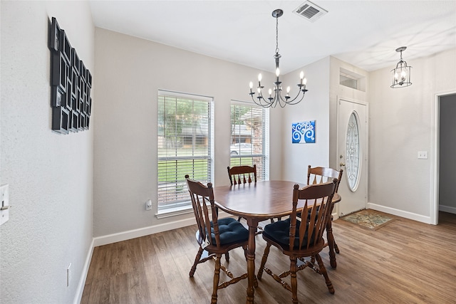 dining area with hardwood / wood-style floors and an inviting chandelier