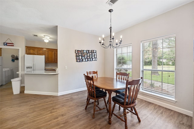 dining room with an inviting chandelier, hardwood / wood-style flooring, and washer and dryer