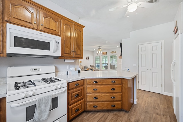 kitchen featuring light hardwood / wood-style flooring, white appliances, and kitchen peninsula