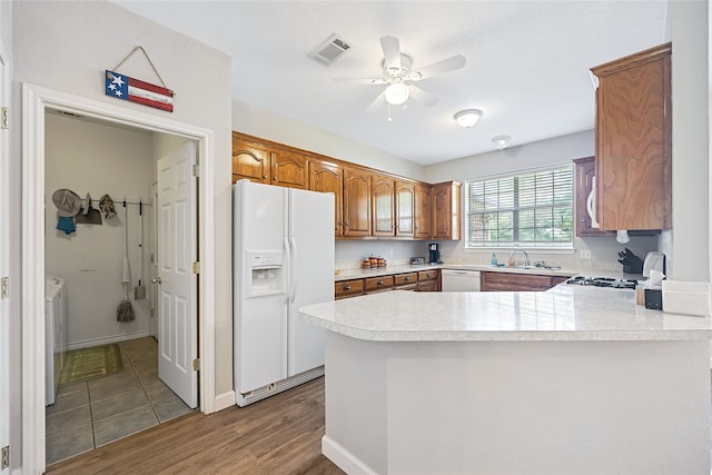 kitchen with white appliances, kitchen peninsula, ceiling fan, and sink