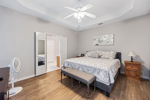 bedroom featuring ceiling fan, a raised ceiling, and hardwood / wood-style floors