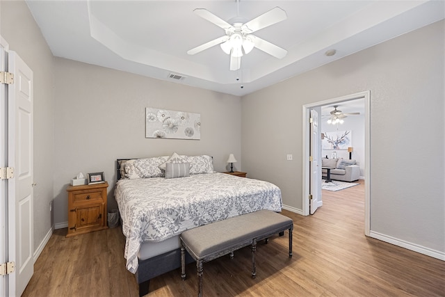 bedroom featuring ceiling fan, hardwood / wood-style floors, and a tray ceiling