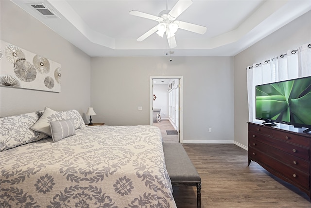 bedroom featuring ceiling fan, wood-type flooring, and a tray ceiling