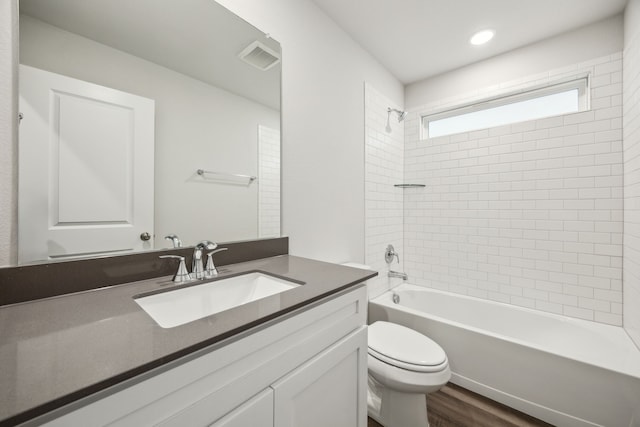 full bathroom featuring tiled shower / bath, wood-type flooring, vanity, and toilet