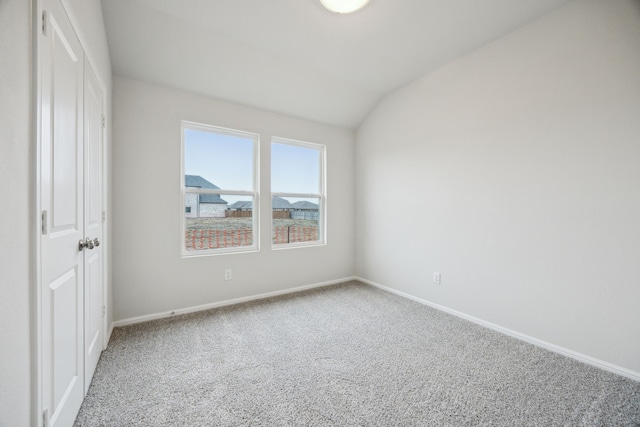 carpeted empty room featuring vaulted ceiling