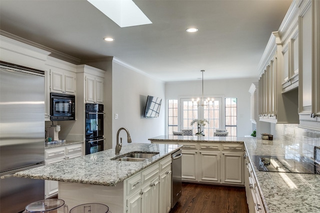 kitchen featuring sink, a kitchen breakfast bar, pendant lighting, a center island with sink, and black appliances