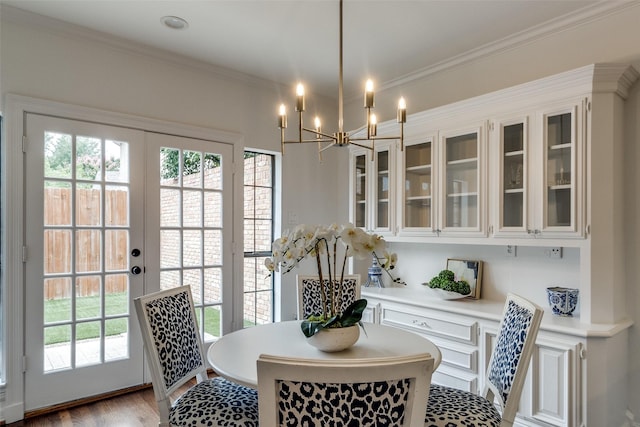 dining space with an inviting chandelier, french doors, crown molding, and wood-type flooring