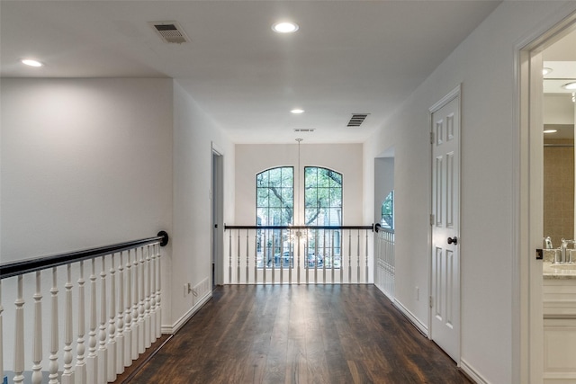 hall with dark wood-type flooring and an inviting chandelier