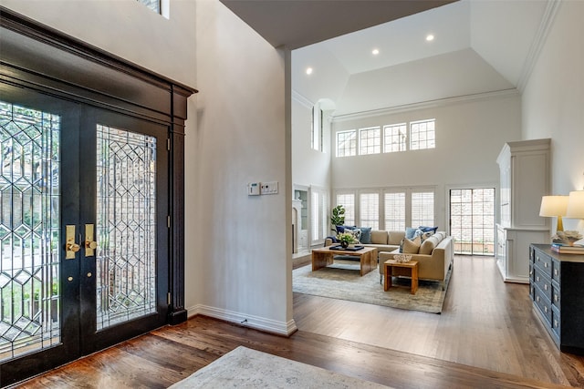 foyer entrance with a towering ceiling, french doors, ornamental molding, and dark wood-type flooring