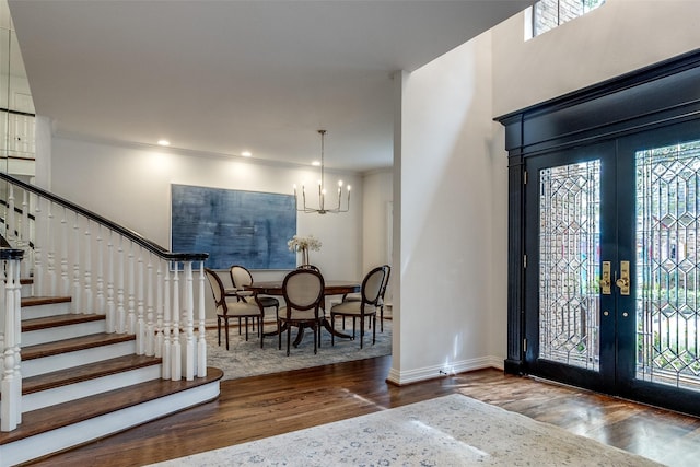 foyer with a notable chandelier, dark hardwood / wood-style flooring, french doors, and crown molding