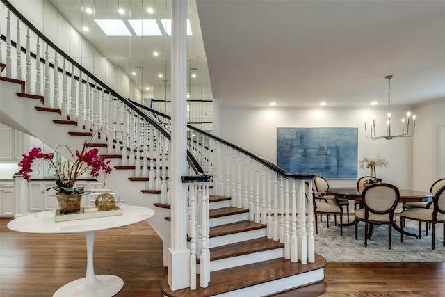 stairs with a notable chandelier, a towering ceiling, and wood-type flooring