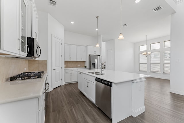 kitchen featuring a kitchen island with sink, an inviting chandelier, stainless steel appliances, white cabinets, and decorative light fixtures