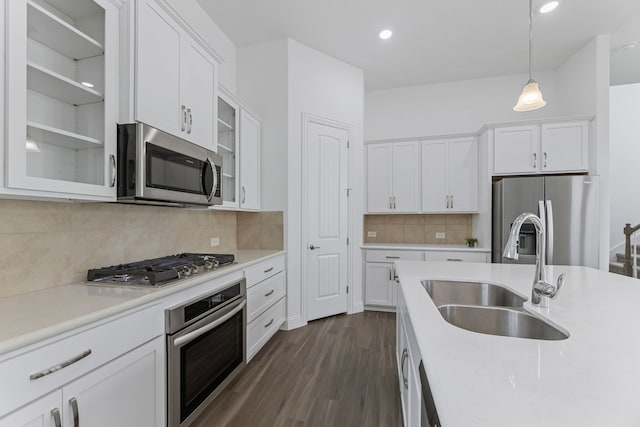 kitchen with decorative light fixtures, appliances with stainless steel finishes, white cabinetry, and sink